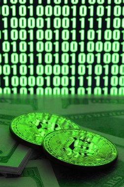 İki bitcoins yalanlar üzerine bir yığın para parlak yeşil sıfır ve bir çift değişkenli bir kod resmeden bir monitör arka plan üzerinde siyah bir zemin üzerine birimleri. Düşük anahtar aydınlatma