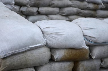 Birçok kirli kum torbası sel savunma için arka plan. Askerî kullanıma yönelik koruyucu kum torbası barikat. Yakışıklı taktik sığınak