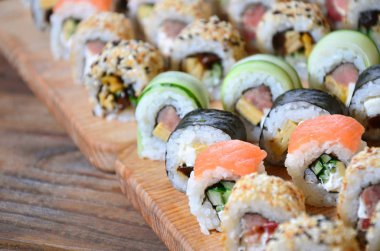 Birçok rulo suşi kümesi bir makro çekim'de bir tabloda bir suşi bar mutfak ahşap kesme tahtası üzerinde yer alır. Japon mutfağının geleneksel yemeği