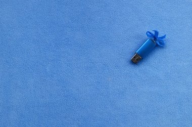 Parlak mavi usb flash bellek kart mavi bir yay ile yumuşak ve tüylü ışık mavi Polar kumaş bir battaniye üzerinde yatıyor. Klasik kadın hediye tasarım a bellek oyun kağıdı için