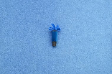 Parlak mavi usb flash bellek kart mavi bir yay ile yumuşak ve tüylü ışık mavi Polar kumaş bir battaniye üzerinde yatıyor. Klasik kadın hediye tasarım a bellek oyun kağıdı için