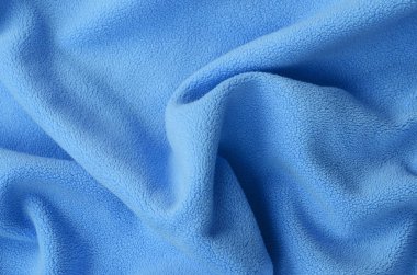 Tüylü mavi Polar kumaş battaniye. Bir arka plan ışık mavi yumuşak peluş Polar malzeme bir sürü kabartma kıvrımları ile