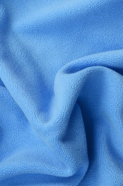 Tüylü mavi Polar kumaş battaniye. Bir arka plan ışık mavi yumuşak peluş Polar malzeme bir sürü kabartma kıvrımları ile