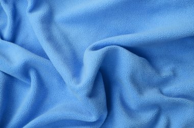 Tüylü mavi Polar kumaş battaniye. Bir arka plan ışık mavi yumuşak peluş Polar malzeme bir sürü kabartma kıvrımları ile