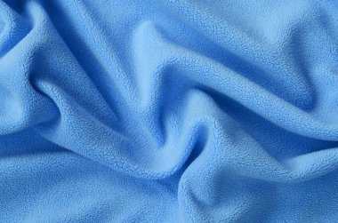 Tüylü mavi Polar kumaş battaniye. Bir arka plan ışık mavi yumuşak peluş Polar malzeme bir sürü kabartma kıvrımları ile