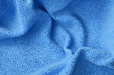 Tüylü mavi Polar kumaş battaniye. Bir arka plan ışık mavi yumuşak peluş Polar malzeme bir sürü kabartma kıvrımları ile