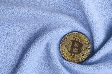 Altın bitcoin yumuşak ve kabarık ışık mavi Polar kumaş çok sayıda kabartma kıvrımları ile yapılmış bir battaniye yatıyor. Kıvrımları şeklinde bir ekran kartı soğutucu fan benzer