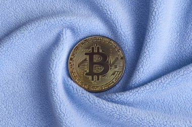 Altın bitcoin yumuşak ve kabarık ışık mavi Polar kumaş çok sayıda kabartma kıvrımları ile yapılmış bir battaniye yatıyor. Kıvrımları şeklinde bir ekran kartı soğutucu fan benzer