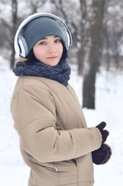 Oldukça çekici beyaz gözlü kız hipster kış park portresi. Kulaklıklar üzerinde müzik dinliyor. Gençlik sokak moda. Kış eğlence.
