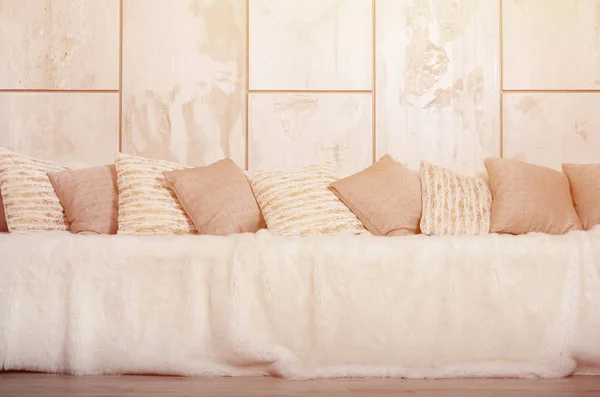 大理石の壁の背景に大きなぬいぐるみのベールで覆われたソファに横に多くの枕 — ストック写真