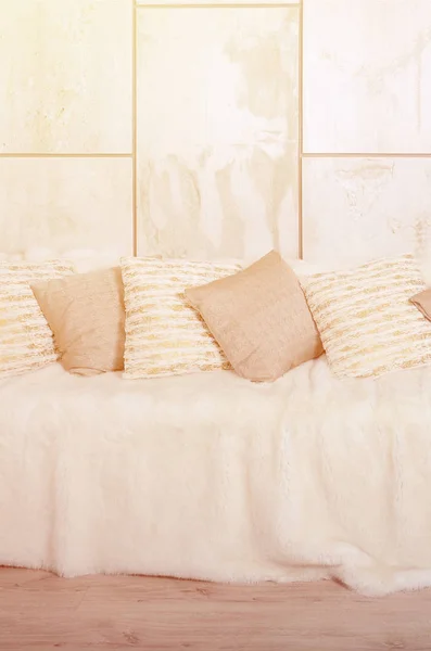 大理石の壁の背景に大きなぬいぐるみのベールで覆われたソファに横に多くの枕 — ストック写真