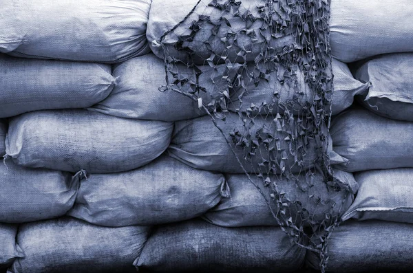 Background of many dirty sand bags for flood defense. Protective sandbag barricade for military use. Handsome tactical bunker