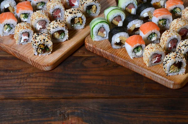 ロール数の寿司セットは 寿司バーのキッチンのテーブルの上に木製のまな板にあります オリエンタル料理の伝統的な料理 — ストック写真
