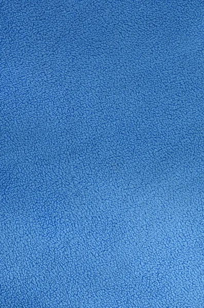 The blanket of furry blue fleece fabric. A background texture of light blue soft plush fleece material
