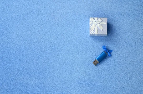 青弓と鮮やかな青い Usb メモリカードは柔らかく 毛皮のような明るい青色フリース生地の毛布の上の小さな弓にブルーの小さなギフト ボックスの横にあります 古典的な女性ギフト メモリ カード デザイン — ストック写真