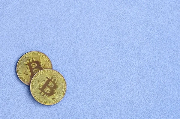İki altın bitcoins yumuşak ve kabarık ışık mavi Polar kumaştan yapılmış bir battaniye yatıyor. Sanal Kripto para biriminin fiziksel görselleştirme