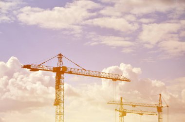 Uzun boylu ve ağır inşaat vinç kule mavi gökyüzünde akşam gün batımına karşı