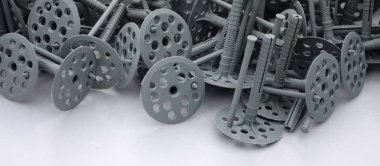 Background of many gray plastic dowels (fastening) for thermal insulation. A huge pile of plastic bolts with round holey hats lies on a gray foam polystyrene plate clipart