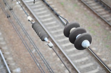 Electrical insulators on the contact wires on the background of a blurred railway track. Macro photo with selective focus clipart