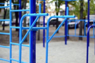 Atletizm eğitimi için arka planda mavi renkli spor barları. Açık havada spor aletleri. Seçici odaklı ve son derece bulanık arkaplanı olan makro fotoğraf