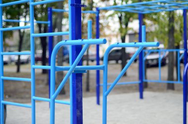Atletizm eğitimi için arka planda mavi renkli spor barları. Açık havada spor aletleri. Seçici odaklı ve son derece bulanık arkaplanı olan makro fotoğraf