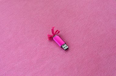 Parlak pembe usb flash bellek kartı pembe bir yay ile yumuşak ve tüylü hafif pembe Polar kumaş bir battaniye üzerinde yatıyor. Klasik kadın hediye tasarım a bellek oyun kağıdı için