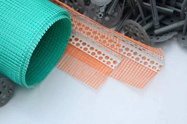 A set of construction items for the insulation of walls. Plastic dowels, a roll of mesh for the insulation of facades and a corner profile with a grid lie on the foam polystyrene surface — Stock Image Set Construction Items Insulation Walls Plastic Dowels Roll Mesh Insulation Royalty Free Stock Images