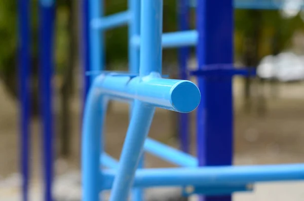 Sports bars in blue on the background of a street sports ground for training in athletics. Outdoor athletic gym equipment. Macro photo with selective focus and extremely blurred background — Stock Image Sports Bars Blue Background Street Sports Ground Training Athletics Outdoor Royalty Free Stock Photos