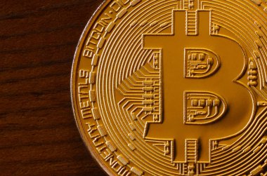 Bir yeni altın fiziksel bitcoin koyu ahşap artalan üzerinde yatıyor, yakın çekim. Yüksek çözünürlüklü fotoğraf. Cryptocurrency incelemesi kavramı