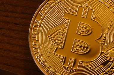 Bir yeni altın fiziksel bitcoin koyu ahşap artalan üzerinde yatıyor, yakın çekim. Yüksek çözünürlüklü fotoğraf. Cryptocurrency incelemesi kavramı