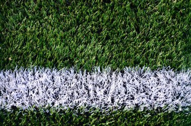 Parlak yeşil yeşil çimen futbol sahasında beyaz şerit.
