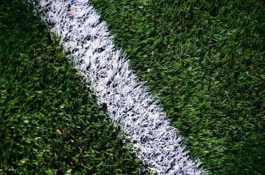 Parlak yeşil yeşil çimen futbol sahasında beyaz şerit.