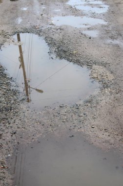 Fotoğraf ile yağmurlu havalarda büyük su birikintileri yok edilen bir yol parçasının