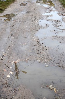 Fotoğraf ile yağmurlu havalarda büyük su birikintileri yok edilen bir yol parçasının