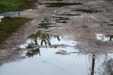 Fotoğraf ile yağmurlu havalarda büyük su birikintileri yok edilen bir yol parçasının