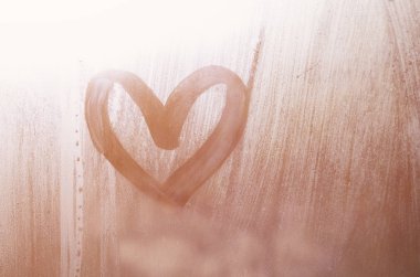 Yağmurlu havalarda misted camına bir parmak tarafından çizilmiş bir kalp şeklinde çizim