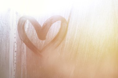 Yağmurlu havalarda misted camına bir parmak tarafından çizilmiş bir kalp şeklinde çizim