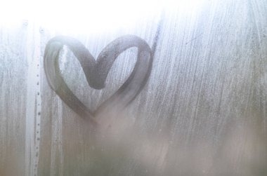 Yağmurlu havalarda misted camına bir parmak tarafından çizilmiş bir kalp şeklinde çizim