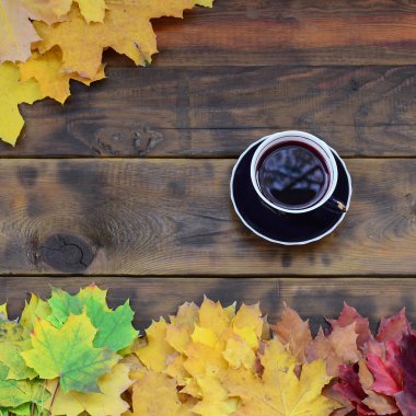 Arka plan koyu kahverengi renk doğal ahşap kurullarında yüzeyinde düşmüş sonbahar sararma kümesi arasında çay yaprakları