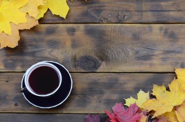 Arka plan koyu kahverengi renk doğal ahşap kurullarında yüzeyinde düşmüş sonbahar sararma kümesi arasında çay yaprakları