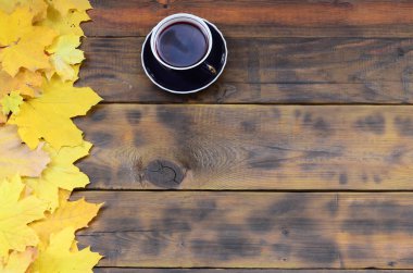 Arka plan koyu kahverengi renk doğal ahşap kurullarında yüzeyinde düşmüş sonbahar sararma kümesi arasında çay yaprakları