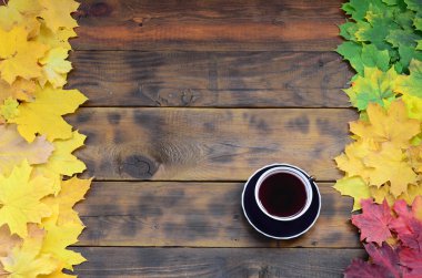 Arka plan koyu kahverengi renk doğal ahşap kurullarında yüzeyinde düşmüş sonbahar sararma kümesi arasında çay yaprakları