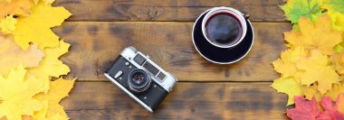 Bir fincan çay ve bir arka plan yüzeyi koyu kahverengi renk doğal ahşap kurulların düşen sonbahar yaprakları sararma kümesi arasında eski bir fotoğraf makinesi