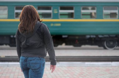 Kızıl saçlı bir kız demiryolu platformu üzerinde duran ve çıkış yapan tren izliyor. Treni için geç bir kadındı. Arkadan Görünüm