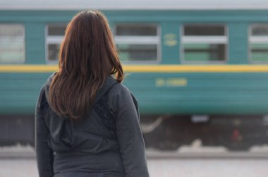 Kızıl saçlı bir kız demiryolu platformu üzerinde duran ve çıkış yapan tren izliyor. Treni için geç bir kadındı. Arkadan Görünüm