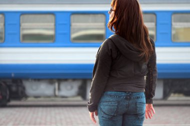 Kızıl saçlı bir kız demiryolu platformu üzerinde duran ve çıkış yapan tren izliyor. Treni için geç bir kadındı. Arkadan Görünüm