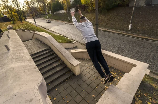 A young guy performs a jump through the space between the concrete parapets. The athlete practices parkour, training in street conditions. The concept of sports subcultures among youth