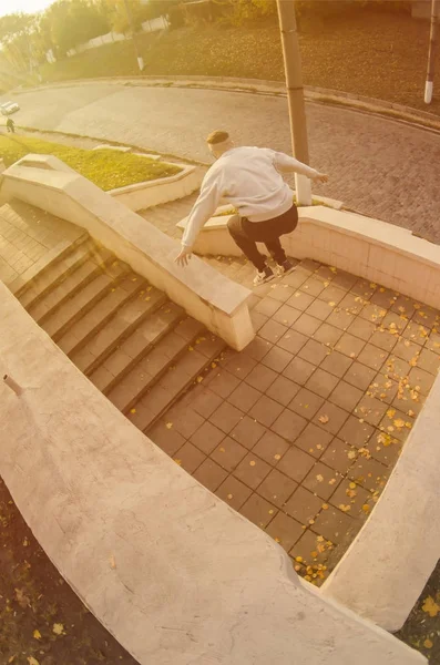 A young guy performs a jump through the space between the concrete parapets. The athlete practices parkour, training in street conditions. The concept of sports subcultures among youth