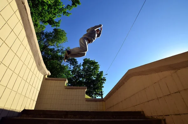 A young guy performs a jump through the space between the concrete parapets. The athlete practices parkour, training in street conditions. Bottom view