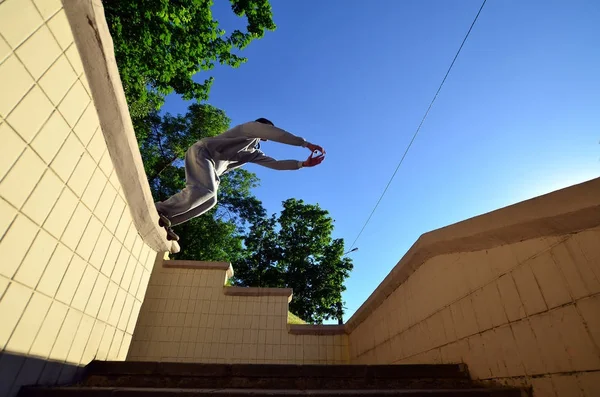 A young guy performs a jump through the space between the concrete parapets. The athlete practices parkour, training in street conditions. Bottom view